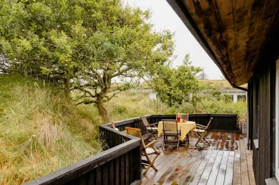a wooden deck with a table and chairs on it at Nordic 70S Gem Amidst The Dunes in Blokhus