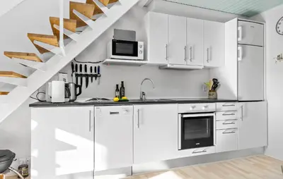 a kitchen with white cabinets and a staircase at Cozy Home In Vestervig With Sauna in Vestervig