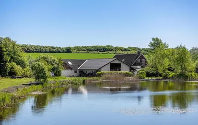 a house next to a river with a house at Beautiful Home In Nibe With Sauna in Nibe