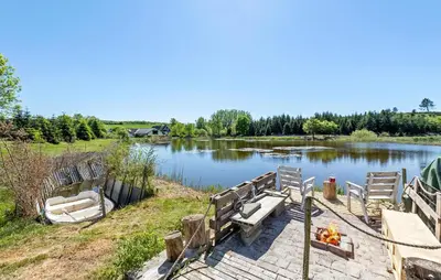 a lake with a dock and two boats on it at Beautiful Home In Nibe With Sauna in Nibe