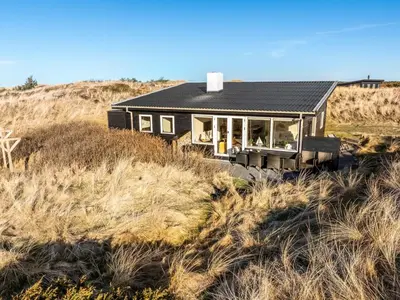 a black house on a hill in a field at Holiday Home Alrike - 200m from the sea by Interhome in Brovst