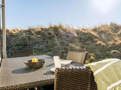 a table with a basket of fruit on top of a beach at Holiday Home Alrike - 200m from the sea by Interhome in Brovst