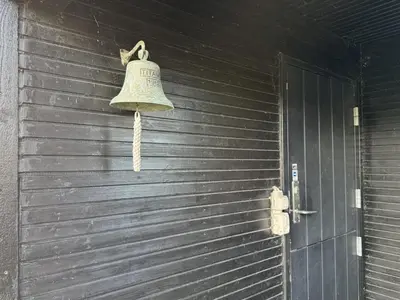 a bell hanging on the side of a wooden door at Holiday Home Alrike - 200m from the sea by Interhome in Brovst