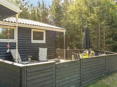 a large deck with an umbrella and a house at Holiday Home Hansa - 3km from the sea by Interhome in Blokhus