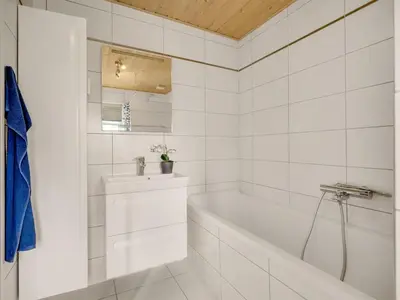 a white bathroom with a tub and a sink at Holiday Home Toska - 3km from the sea by Interhome in Blokhus