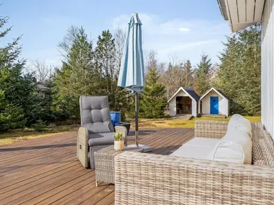 a patio with a couch and a chair and an umbrella at Holiday Home Toska - 3km from the sea by Interhome in Blokhus