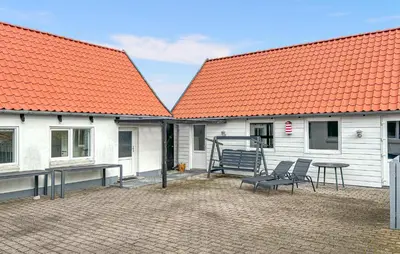 two white buildings with orange roofs with chairs and a table at Gorgeous Home In Thisted With Wifi in Thisted