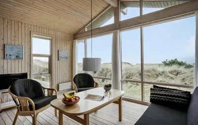 a living room with a table and chairs and windows at Cozy Home In Saltum With House Sea View in Saltum