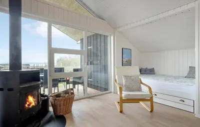 a room with a fireplace and a bed and a chair at 3 Bedroom Amazing Home In Spøttrup in Spottrup