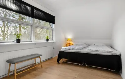 a bedroom with a bed and a chair and windows at 3 Bedroom Cozy Home In Farsø in Farsø