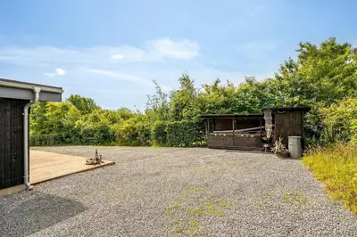 a parking lot with a building and a wooden deck at Charming little cottage in Roslev