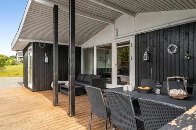 a patio with a table and chairs on a deck at Charming little cottage in Roslev