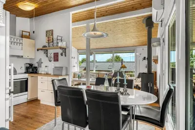 a kitchen and dining room with a table and chairs at Charming little cottage in Roslev