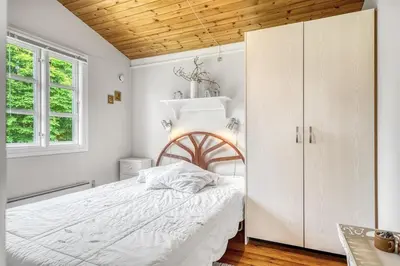 a bedroom with a white bed and a white cabinet at Charming little cottage in Roslev