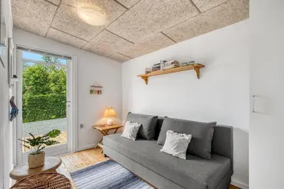 a living room with a couch and a window at Charming little cottage in Roslev