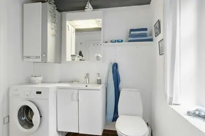 a white bathroom with a washing machine and a toilet at Natural Gem Between Heath And Dunes in Thisted