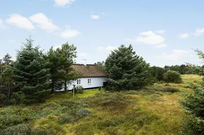 a white house in a field with trees at Natural Gem Between Heath And Dunes in Thisted