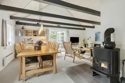 a living room with a table and a wood stove at Natural Gem Between Heath And Dunes in Thisted