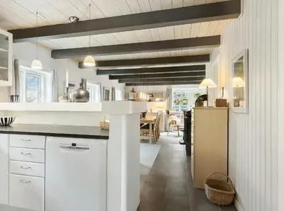a kitchen with white cabinets and a dining room at Natural Gem Between Heath And Dunes in Thisted