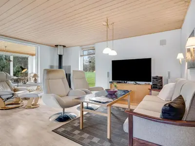 a living room with a table and chairs and a tv at Holiday Home Marika - 400m to the fjord by Interhome in Spottrup