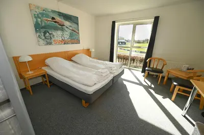 a bedroom with a bed and a table and a window at Sport & Academy in Farsø