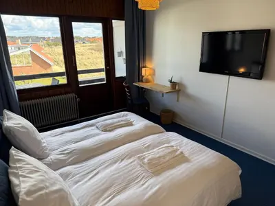 a hotel room with a bed and a flat screen tv at VØ Drop Inn in Nørre Vorupør