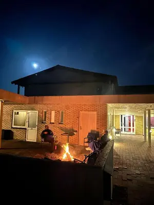 a man sitting around a fire in a courtyard at night at VØ Drop Inn in Nørre Vorupør