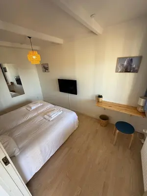 a bedroom with a white bed and a television at VØ Drop Inn in Nørre Vorupør