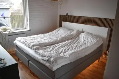 an unmade bed in a bedroom with a window at Viking Surf Camp in Klitmøller