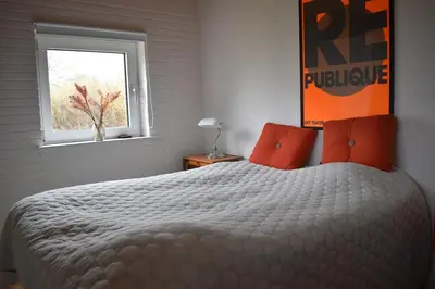 a bedroom with a bed with orange pillows and a window at Viking Surf Camp in Klitmøller