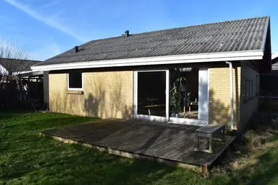 a house with a wooden deck in the yard at Viking Surf Camp in Klitmøller