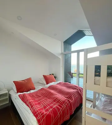 a bedroom with a bed with a red plaid blanket at Architect-Designed House With Private Beach in Løgstrup