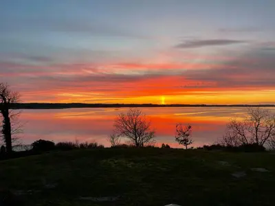 a sunset over a large body of water at Architect-Designed House With Private Beach in Løgstrup