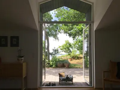 an open door to a patio with a chair outside at Architect-Designed House With Private Beach in Løgstrup