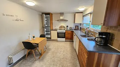 a kitchen with a counter and a table with chairs at Nattely i Thy in Thisted