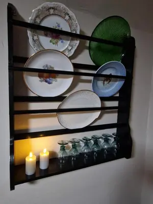 a shelf with plates and candles on a wall at Stædets lejlighed in Bøvlingbjerg