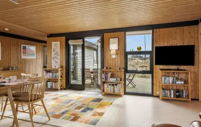 a living room with wooden walls and a table and a tv at 5 Bedroom Lovely Home In Saltum in Saltum