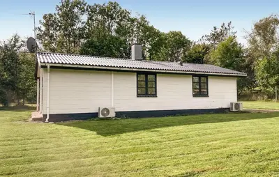 a small white house in a grassy field at Stunning Home In Øster Assels With Wifi in Øster Assels