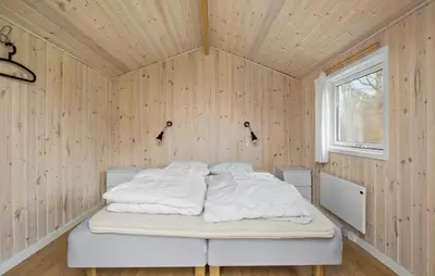 a bedroom with a bed in a wooden wall at Lovely Home In Fjerritslev With Sauna in Fjerritslev