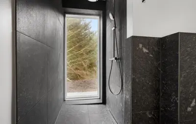 a bathroom with a shower and a window at Beach Front Home In Thyholm With Sauna in Thyholm