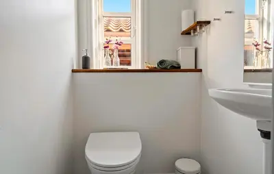 a bathroom with a toilet and a sink and a window at Cozy Home In Spøttrup With Wifi in Lihme