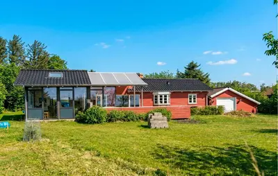 a red house with a solar roof on a yard at Cozy Home In Spøttrup With Wifi in Lihme