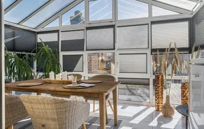 a conservatory with a wooden table and chairs at Amazing Home In Thyborøn With Sauna in Thyborøn