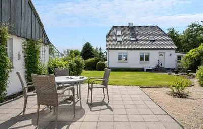a patio with a table and chairs and a house at Nice Home In Farsø With Wifi in Farsø