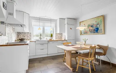 a kitchen with white cabinets and a wooden table at Nice Home In Farsø With Wifi in Farsø