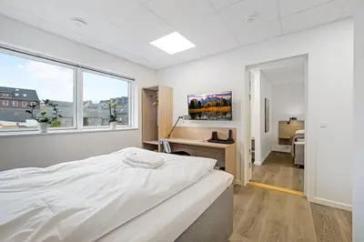 a white bedroom with a bed and a desk at Hotel Thisted in Thisted