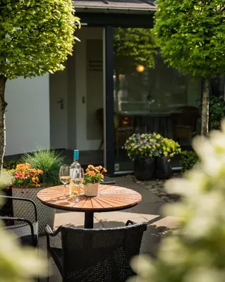 a wooden table with two glasses and a bottle of wine at Hotel Thisted in Thisted