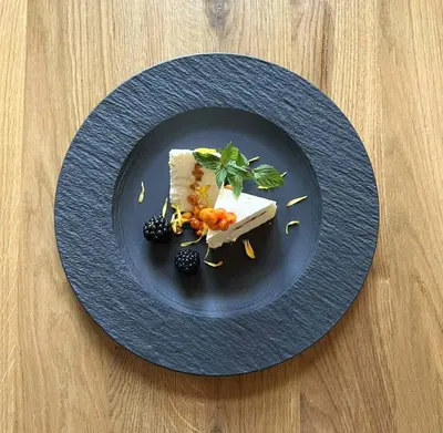 a blue plate with a piece of cheese and fruit at Hotel Thisted in Thisted