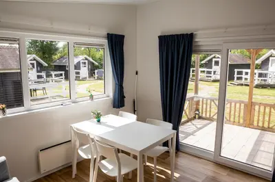 a dining room with a white table and chairs and windows at Holstebro Søpark in Holstebro