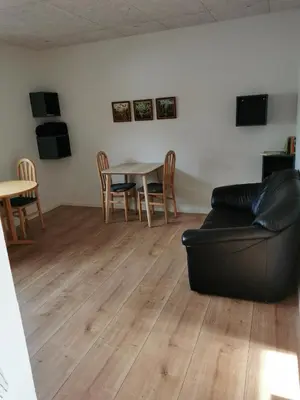 a living room with a couch and a table and chairs at Ferielejlighed in Nibe